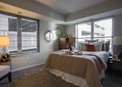 Thumbnail 1 of 10 - a bedroom with a bed and two windows