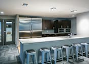 Thumbnail 1 of 19 - a large kitchen with a bar with blue stools