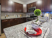 Thumbnail 6 of 10 - a kitchen with granite counter tops and wooden cabinets