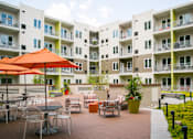 Thumbnail 14 of 19 - an outdoor patio at an apartment complex with tables and umbrellas