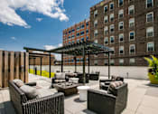 Thumbnail 15 of 19 - a rooftop patio with wicker furniture and a wooden fence