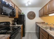 Thumbnail 14 of 26 - A kitchen with black appliances and wooden cabinets. at Meadows Apartments, Emmaus, 18049