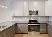 Thumbnail 16 of 35 - A modern kitchen with stainless steel appliances and white cabinets at The Standard Apartments, Allentown, PA