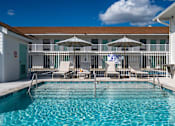 Thumbnail 16 of 21 - a resort style pool with chairs and umbrellas in front of a building at The Teale Navy Yard, North Charleston, South Carolina