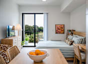 Thumbnail 1 of 58 - A bowl of oranges sits on a wooden table in a well-lit room with a bed and a television.at The Teale Golden Gate in Naples, FL, 34116