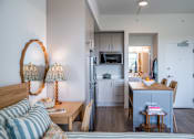 Thumbnail 2 of 58 - A bedroom with a bed, a desk with a chair, and a kitchen area with a refrigerator, microwave, and cabinets.at The Teale Golden Gate in Naples, FL, 34116