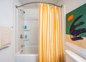 Thumbnail 4 of 58 - A bathroom with a white tub and a yellow shower curtain.at The Teale Golden Gate in Naples, FL, 34116