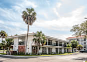 Thumbnail 8 of 58 - A white building with a balcony and a palm tree in front.at The Teale Golden Gate in Naples, FL, 34116