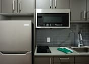 Thumbnail 13 of 58 - A kitchen with a refrigerator, microwave, and sink.