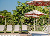 Thumbnail 17 of 58 - A pool with a 4 foot deep sign and chairs under umbrellas.