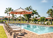 Thumbnail 20 of 58 - A pool surrounded by lawn chairs and umbrellas.