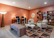 Thumbnail 43 of 58 - A living room with a striped ottoman, a white table, and a rug with a geometric pattern.
