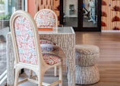 Thumbnail 52 of 58 - A chair with a patterned cushion is placed in front of a glass table.