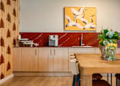 Thumbnail 41 of 58 - A kitchen with a wooden table and a painting of birds on the wall.