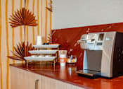 Thumbnail 39 of 58 - A coffee machine is on a counter with a stack of white plates and cups.