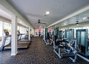Thumbnail 54 of 58 - A spacious gym with treadmills, exercise machines, and a ceiling fan.