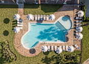 Thumbnail 16 of 58 - An aerial view of a swimming pool surrounded by lawn chairs and umbrellas.