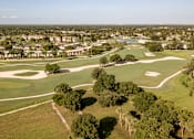 Thumbnail 34 of 58 - A golf course with a green and a tree in the foreground.