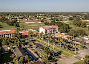 Thumbnail 32 of 58 - A large building with a red roof is surrounded by a parking lot.