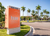 Thumbnail 21 of 58 - A sign for The Teale Golden Gate Apartments stands in front of a row of palm trees.