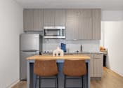 Thumbnail 10 of 21 - a kitchen with stainless steel appliances and a island with two chairs at The Teale Navy Yard, North Charleston, SC, 29405