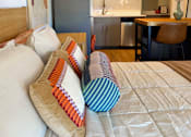 Thumbnail 8 of 16 - A bed with four pillows in front of a kitchen at The Teale Siesta Lago in Kissimmee, FL, 34746