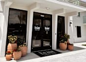 Thumbnail 5 of 16 - The front of a white building with a black door and windows. at The Teale Siesta Lago in Kissimmee, FL, 34746
