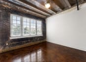 Thumbnail 14 of 40 - an empty room with wood floors and a brick wall and a window
