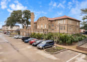 Thumbnail 36 of 40 - a large brick building with cars parked in a parking lot