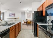 Thumbnail 24 of 40 - full kitchen with stainless steel appliances and wood cabinets and a dining room with a table