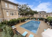 Thumbnail 2 of 40 - a swimming pool with lounge chairs in front of a building