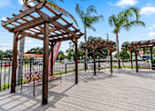 Thumbnail 16 of 16 - A wooden pergola with benches is situated in a park at The Teale Siesta Lago in Kissimmee, FL, 34746