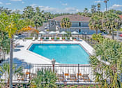 Thumbnail 4 of 11 - a swimming pool with chairs around it and a building in the background at The Teale, Kissimmee, FL, 34746