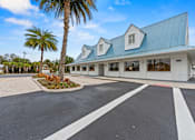 Thumbnail 20 of 20 - A white building with a blue roof and a palm tree in front.