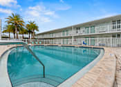 Thumbnail 18 of 20 - A swimming pool in front of a building with palm trees.