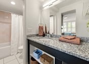 Thumbnail 16 of 20 - A bathroom with a marble countertop and a large mirror.