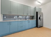 Thumbnail 12 of 20 - A kitchen with blue cabinets and a black refrigerator.