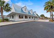 Thumbnail 19 of 20 - A white building with a blue roof is surrounded by palm trees.