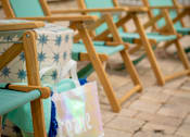 Thumbnail 7 of 20 - A row of blue and white beach chairs are lined up on a patio.