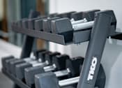 Thumbnail 5 of 20 - A close up of a TKO branded dumbbell rack with grey dumbbells.
