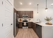 Thumbnail 14 of 15 - A modern kitchen with wooden cabinets and stainless steel appliances.