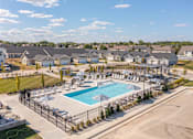 Thumbnail 16 of 31 - A large swimming pool surrounded by a fence and lounge chairs in front of a residential area.