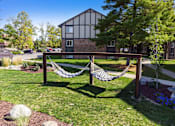 Thumbnail 15 of 25 - A hammock is strung between two wooden posts in a grassy area.