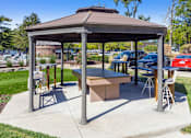 Thumbnail 16 of 25 - A gazebo with a table and chairs is set up in a park.