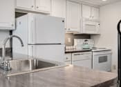 Thumbnail 3 of 25 - A kitchen with a white fridge and a stainless steel sink.