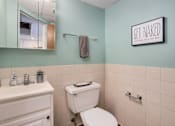 Thumbnail 9 of 25 - A bathroom with a toilet, sink, mirror, and a sign that says "Get Naked".