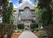 Thumbnail 24 of 25 - A modern building with a grey facade and a symmetrical design is surrounded by greenery.