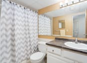 Thumbnail 12 of 25 - A bathroom with a white toilet, a sink, and a shower curtain.
