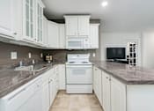 Thumbnail 2 of 25 - A kitchen with white cabinets and a granite countertop.