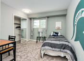 Thumbnail 6 of 25 - A bedroom with a bed, a chair, and a desk.